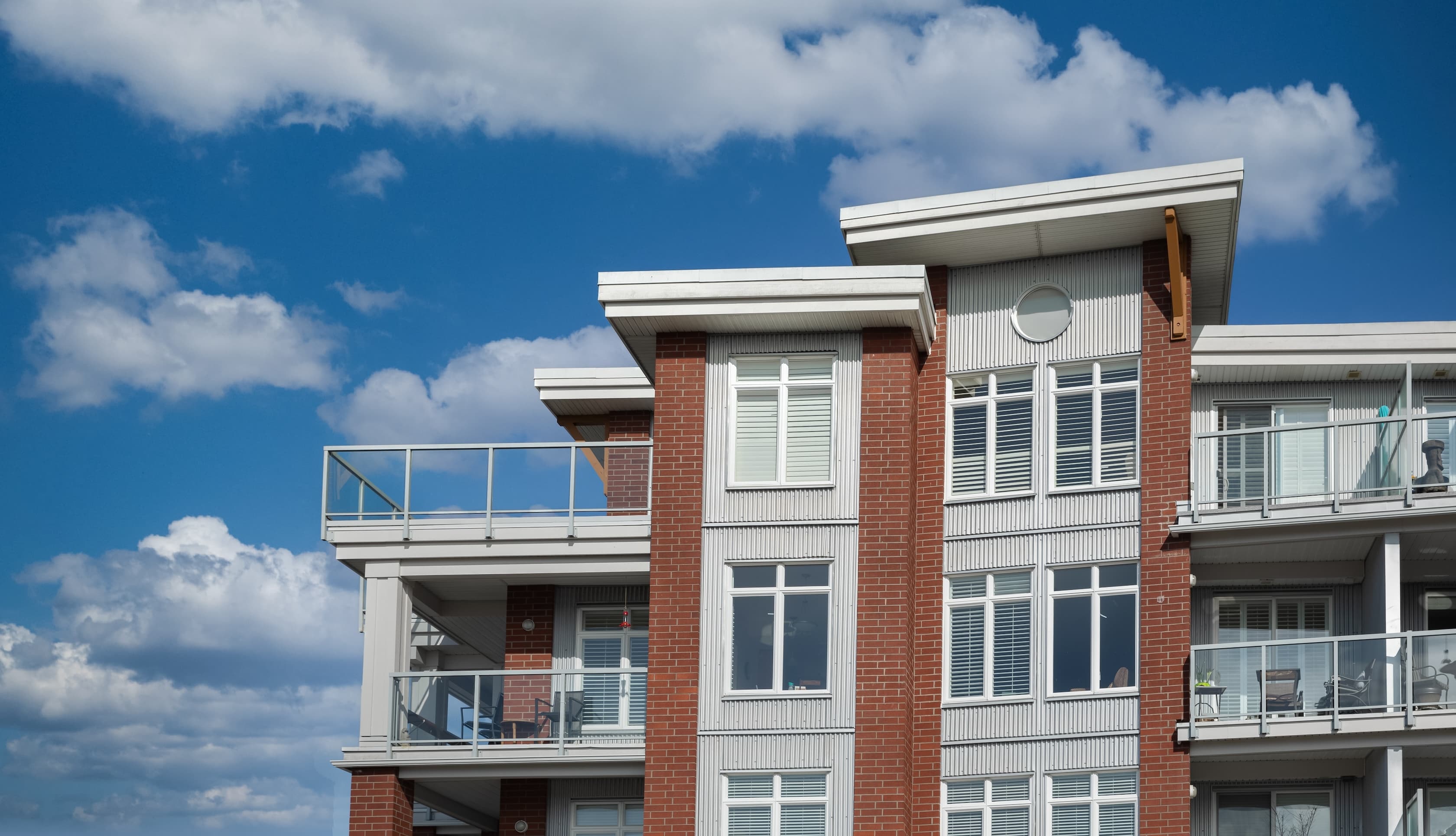 Modern apartment building with brick facade under a blue sky.