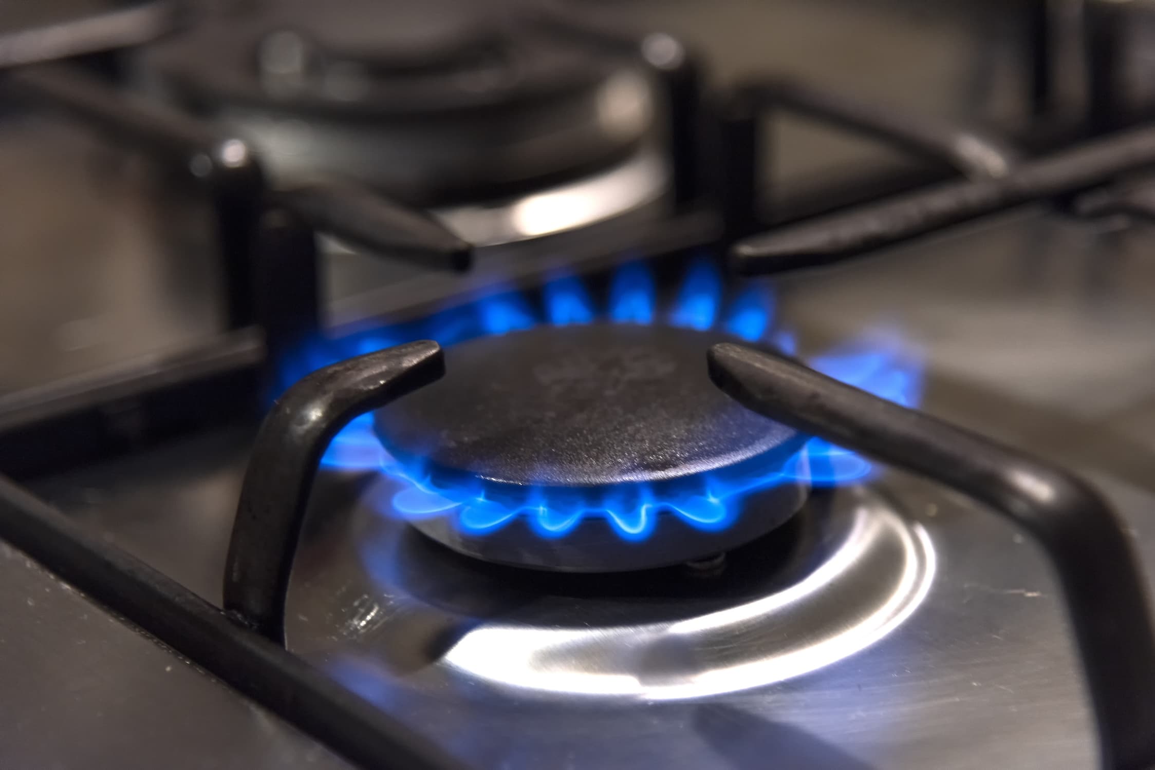 Close-up of gas stove burner with blue flame.