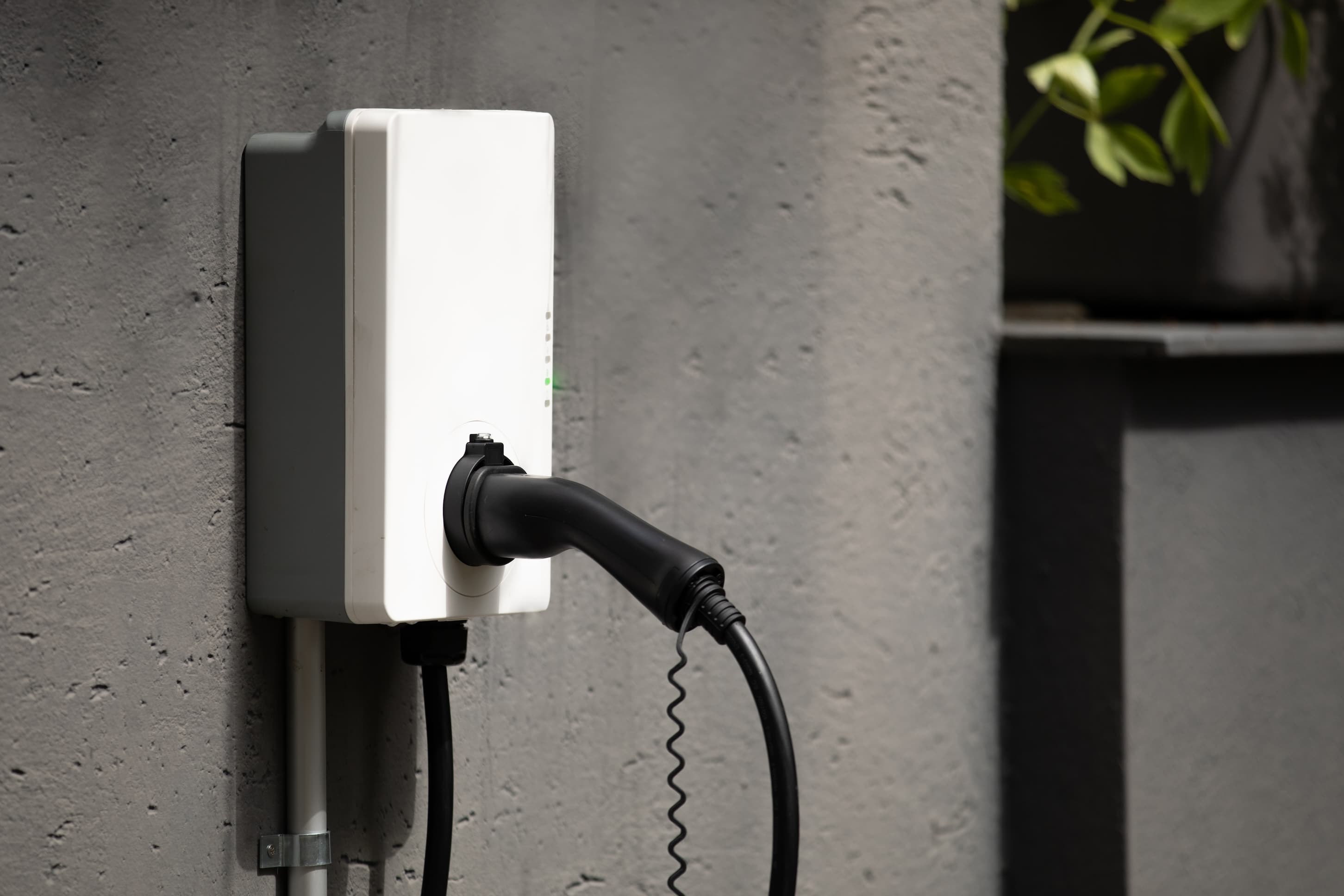 Close-up of an electric vehicle charging station on a concrete wall.