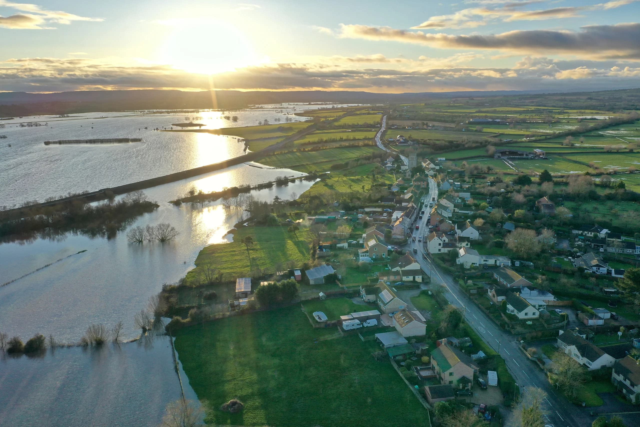 Aerial view of flooded countryside with sunset reflection.