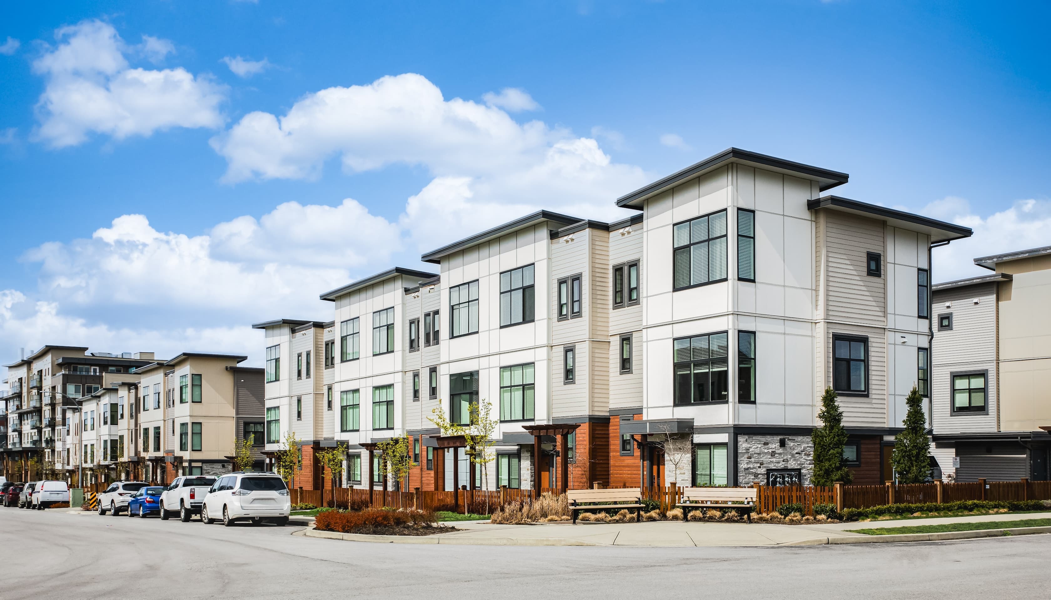 Row of modern townhouses in a suburban setting with clear skies.