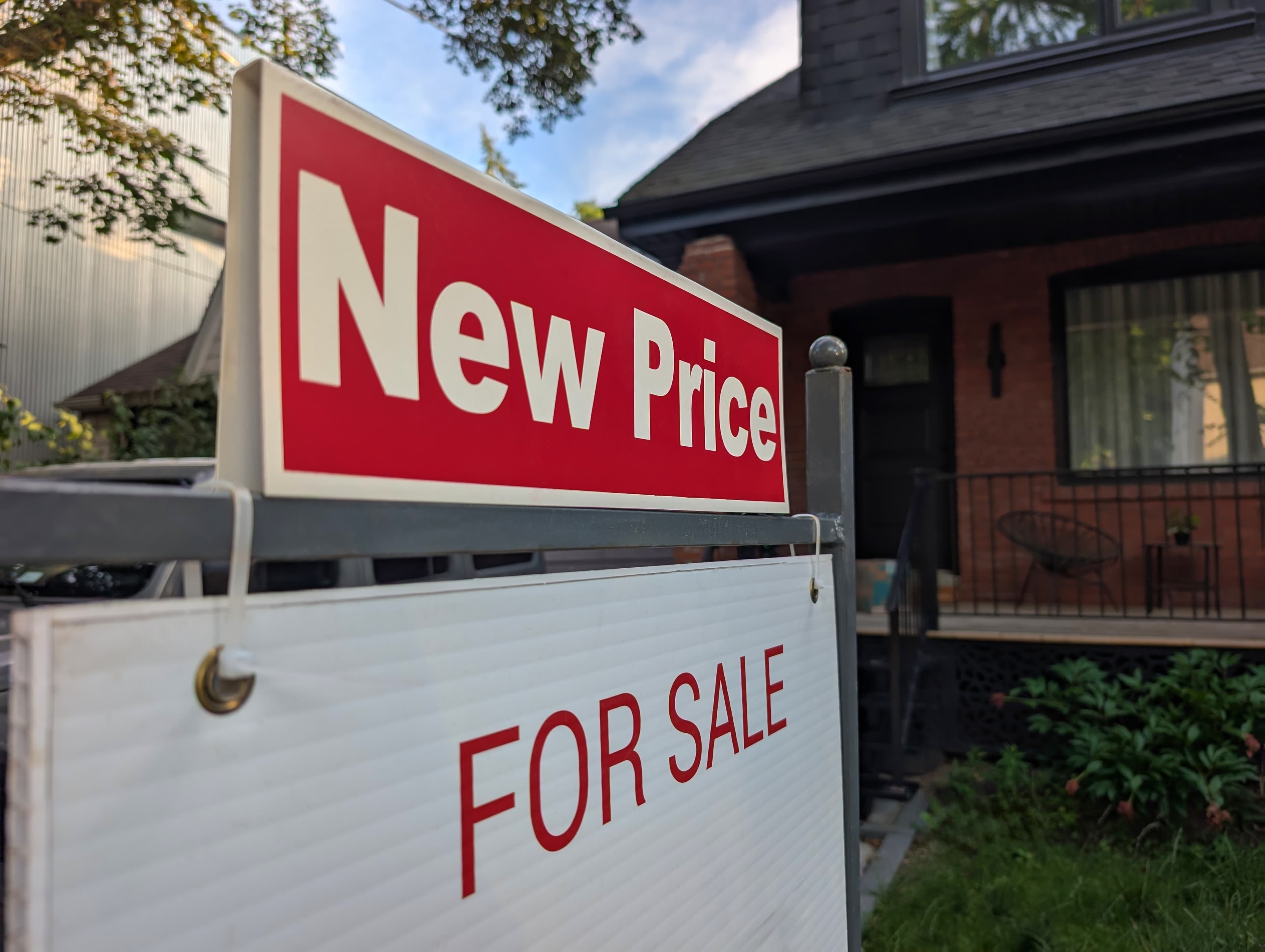 Close-up of 'New Price' real estate sign outside a house.