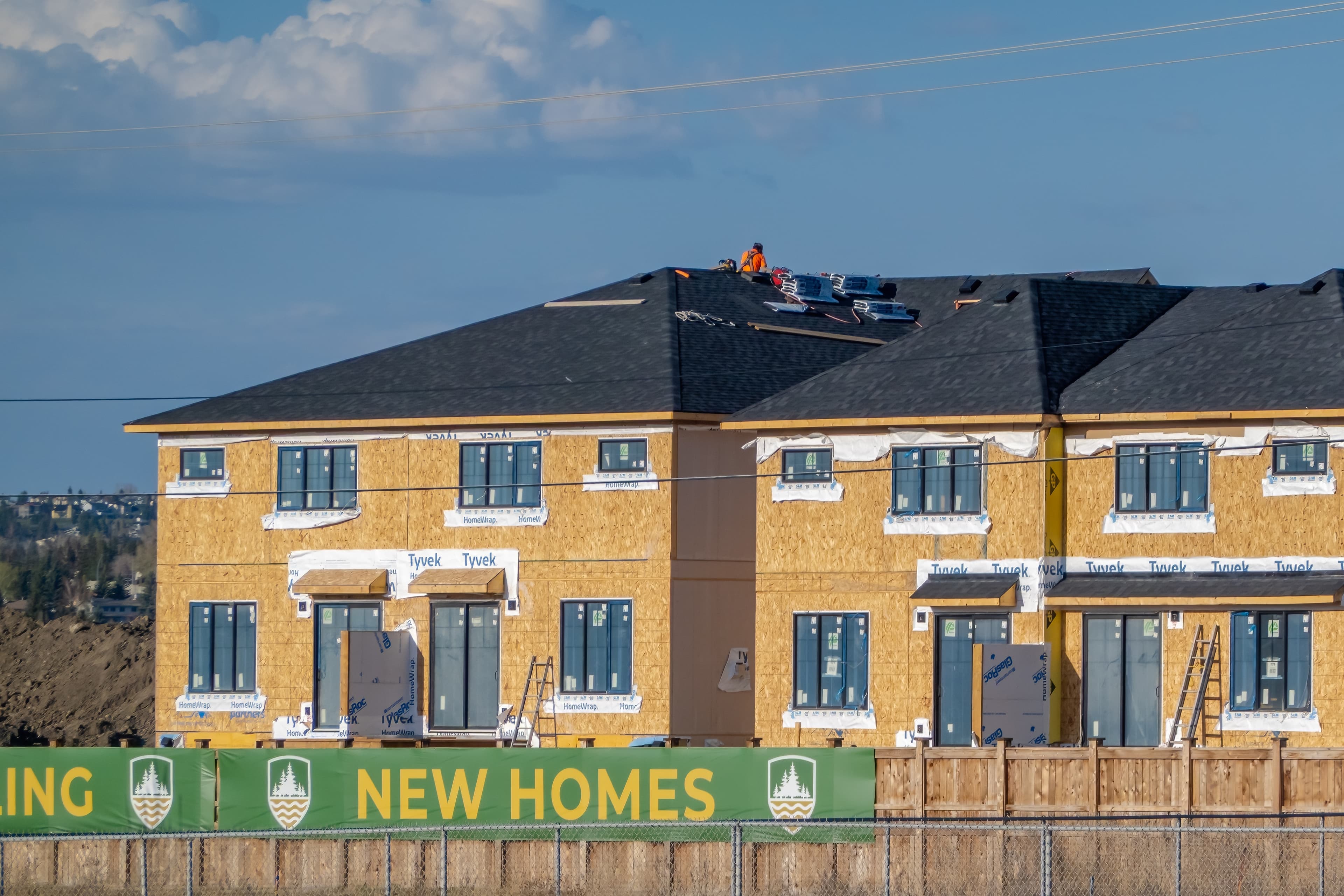 Residential building construction with Tyvek wrap and rooftop worker.