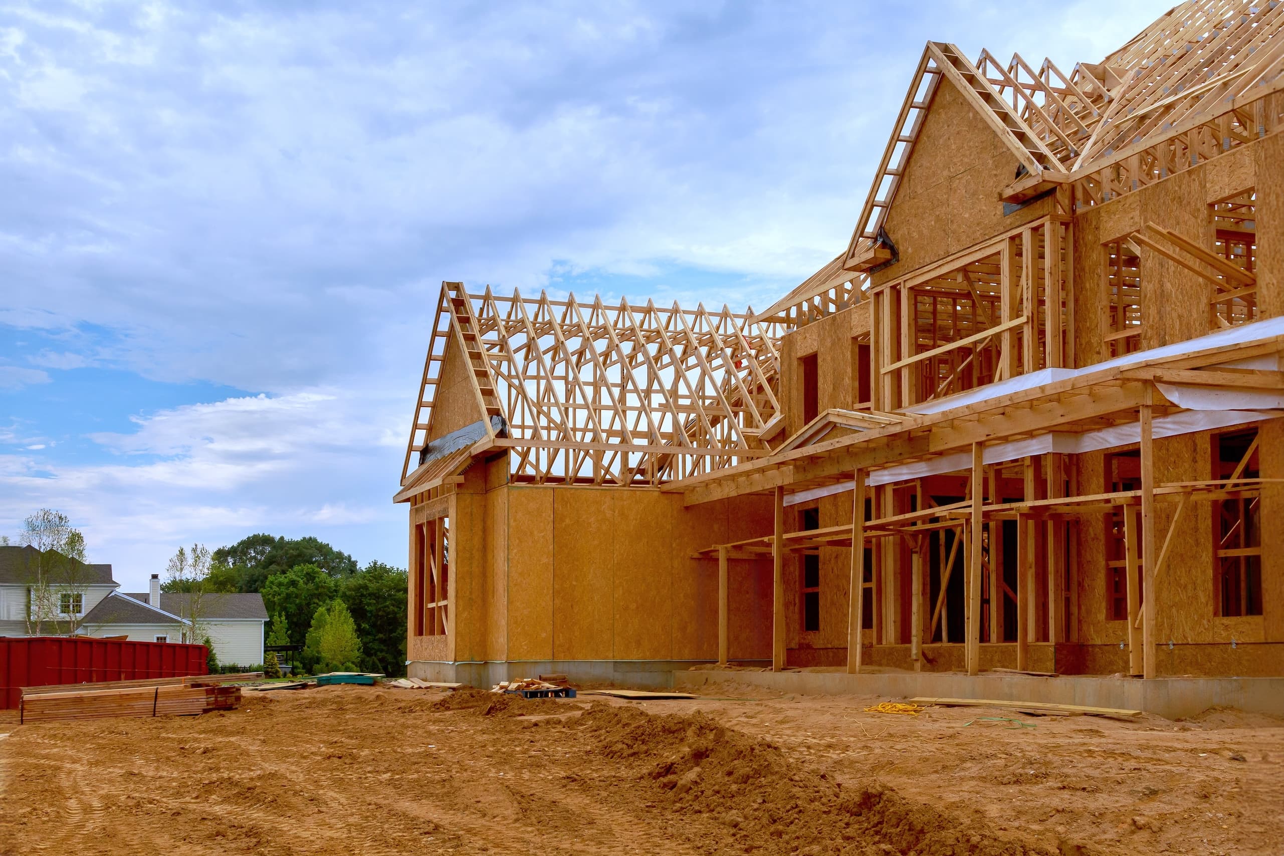 Partially constructed house with wooden framing under cloudy sky.
