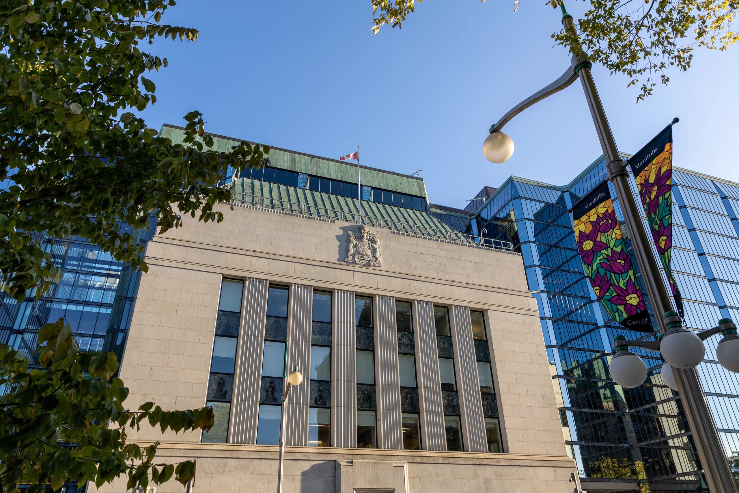 Government building with Canadian flag and nearby modern architecture.
