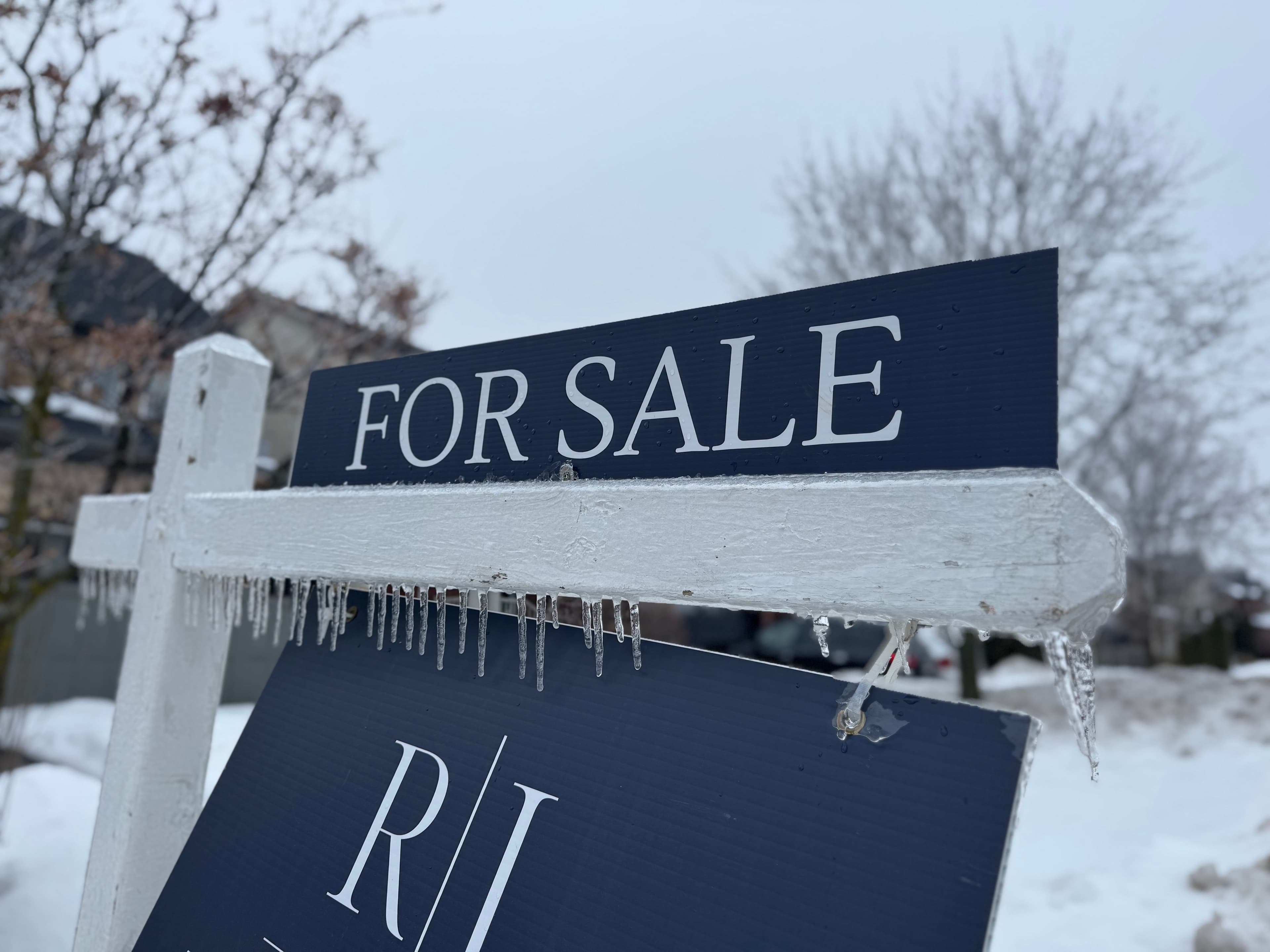 For Sale sign in a snowy winter landscape with icicles.