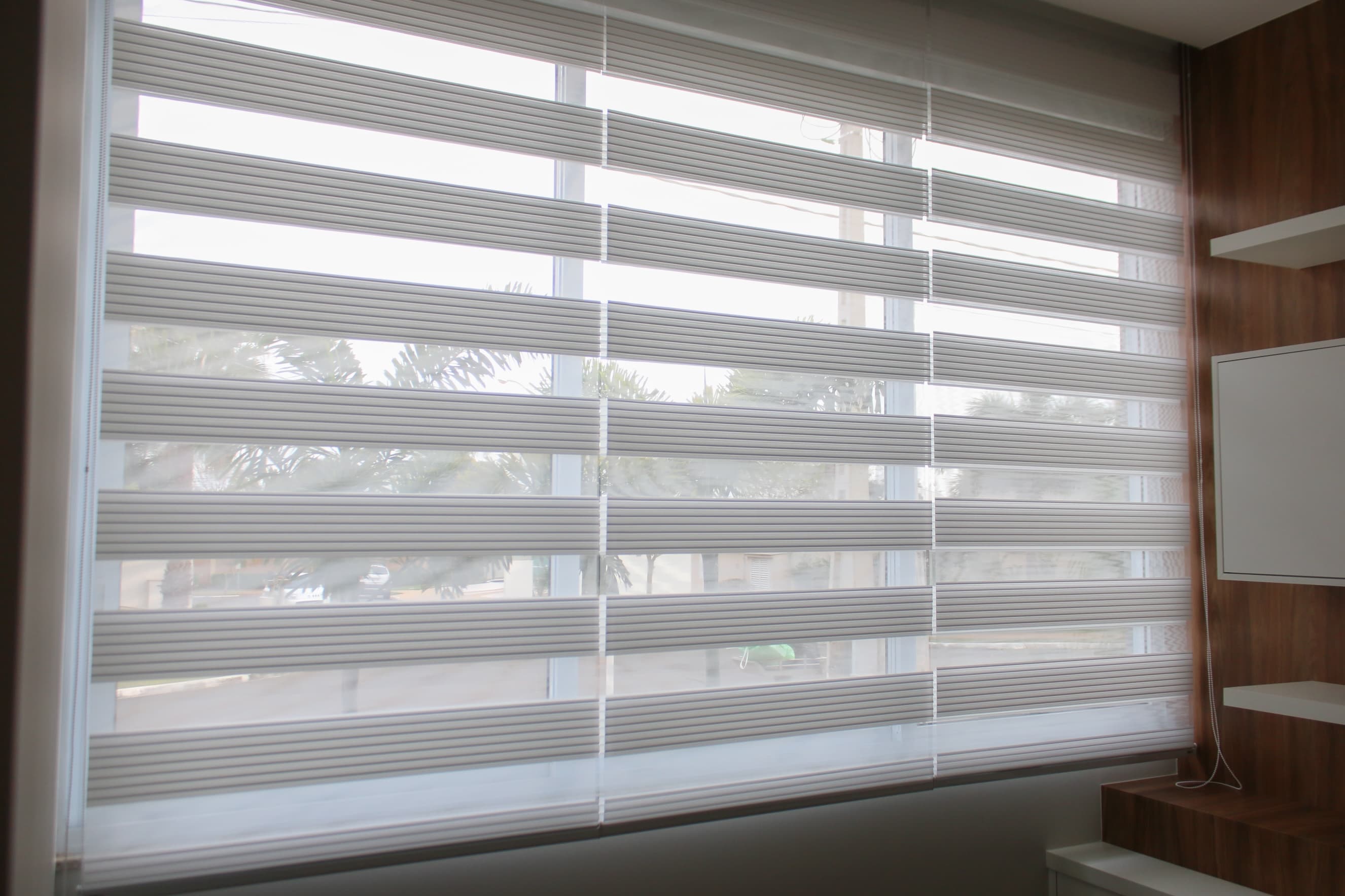 Modern white window blinds filtering light in a home office.