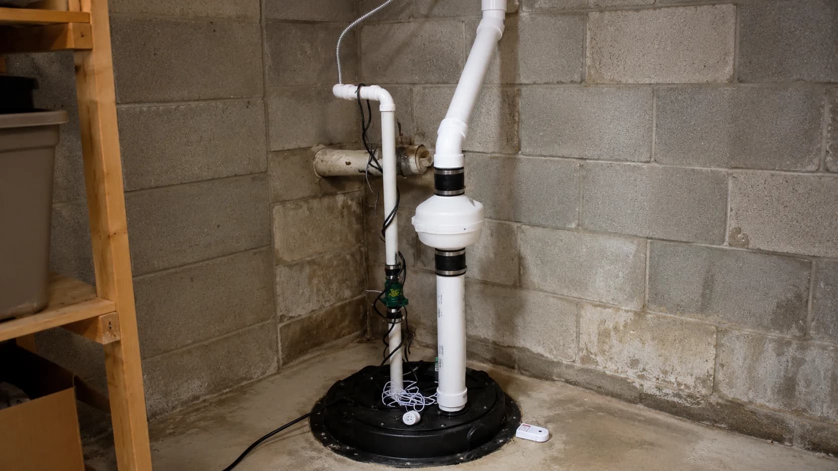 Radon mitigation system installed in basement with PVC piping and fan unit.