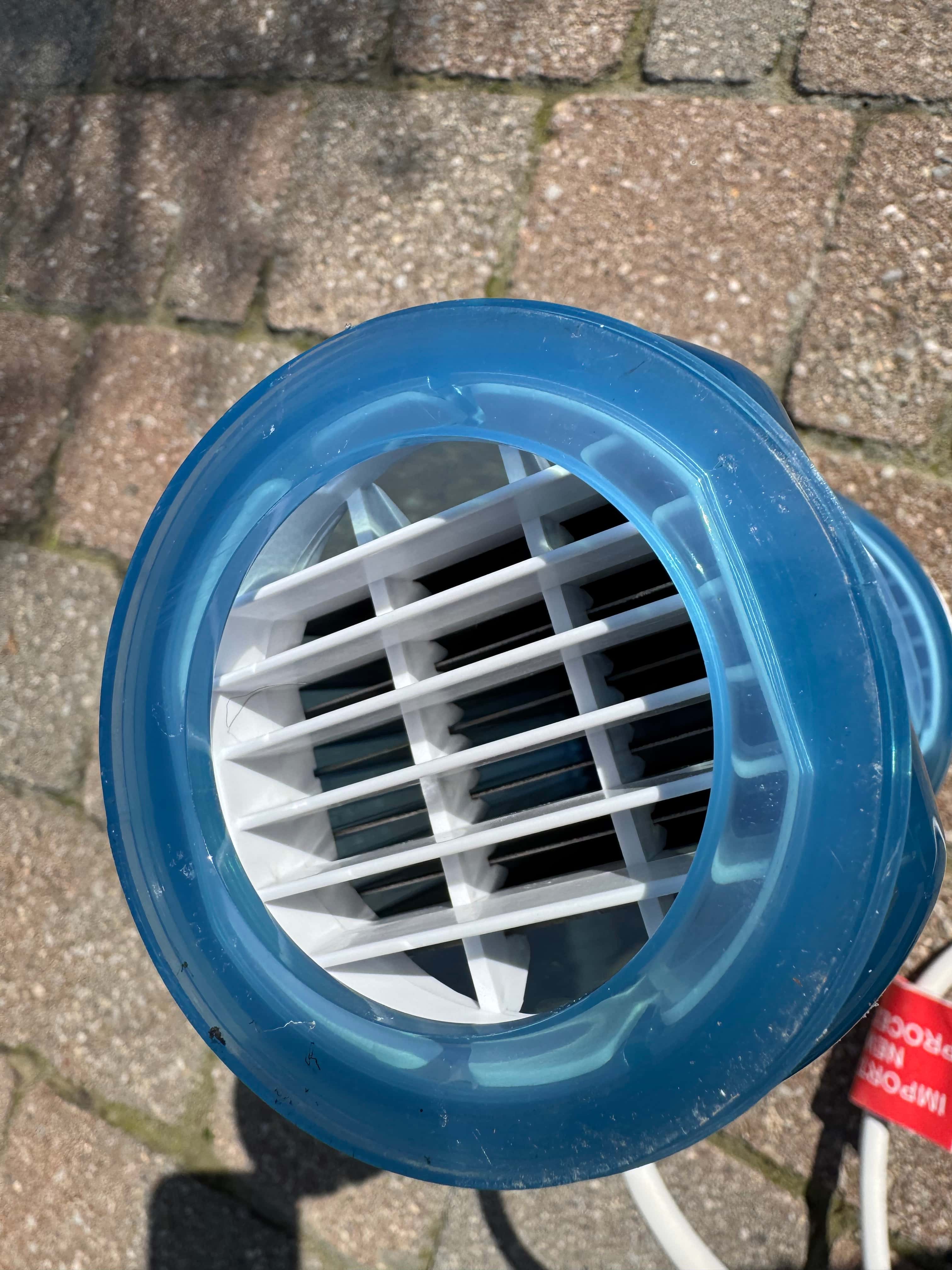 Close-up view of a blue salt cell with white grilles on stone pavement.