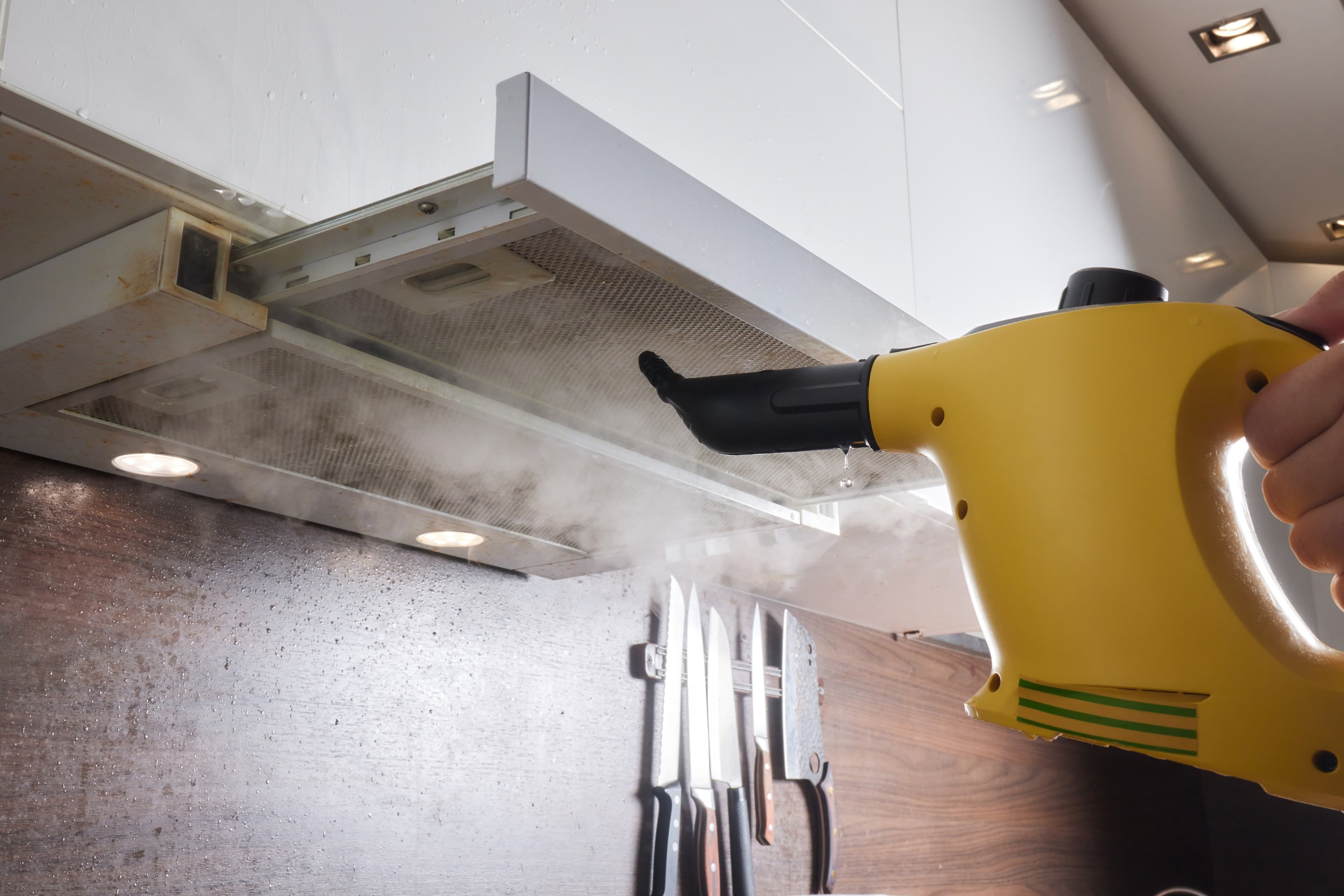 Steam cleaner cleaning a kitchen exhaust hood.