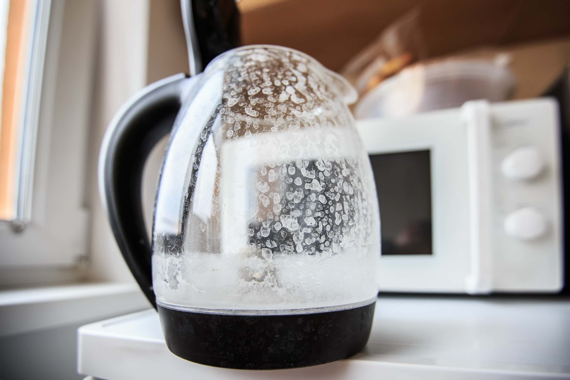 Close-up of a glass kettle with hard water stains on its surface.