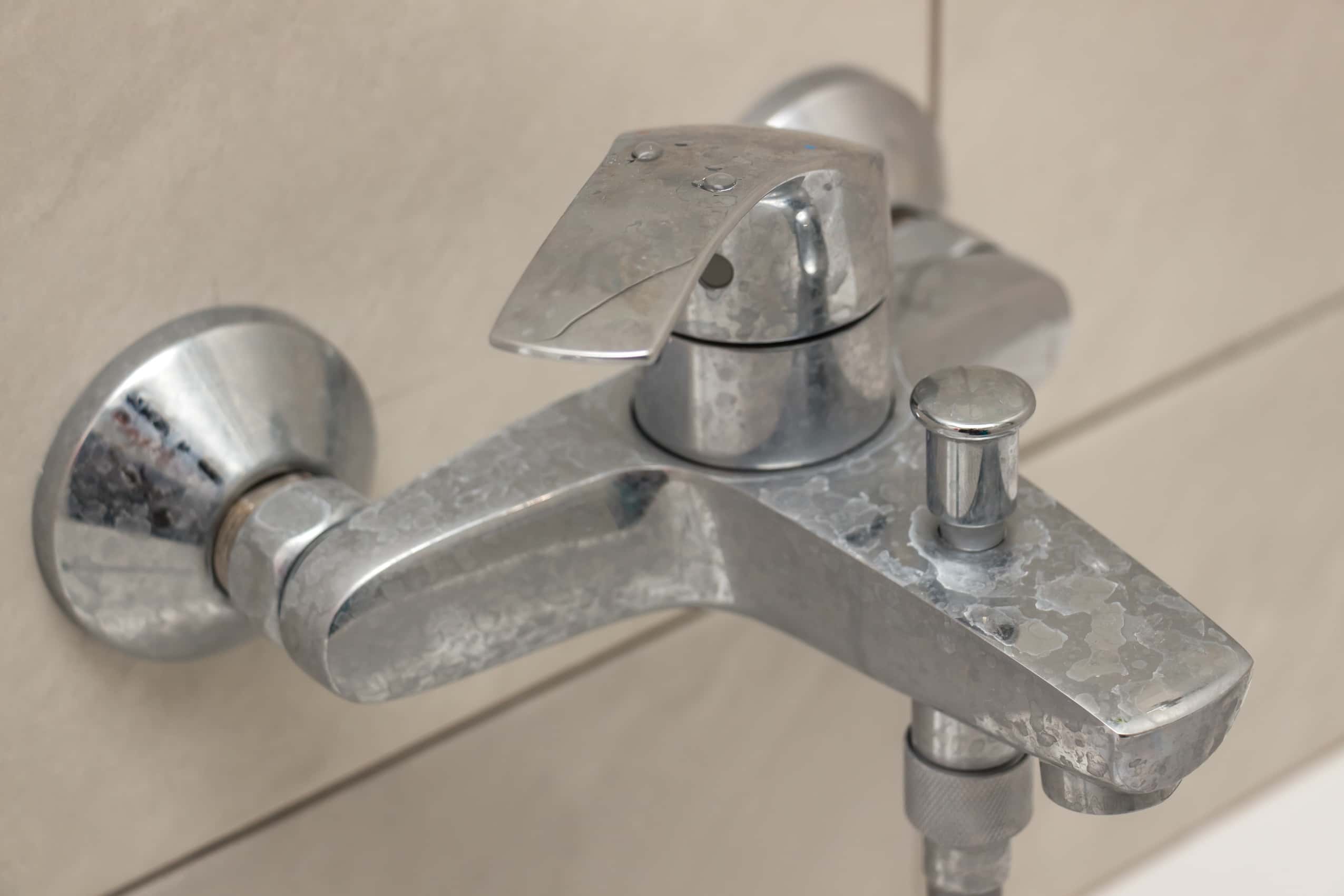 Close-up of a bathroom faucet with hard water stains.