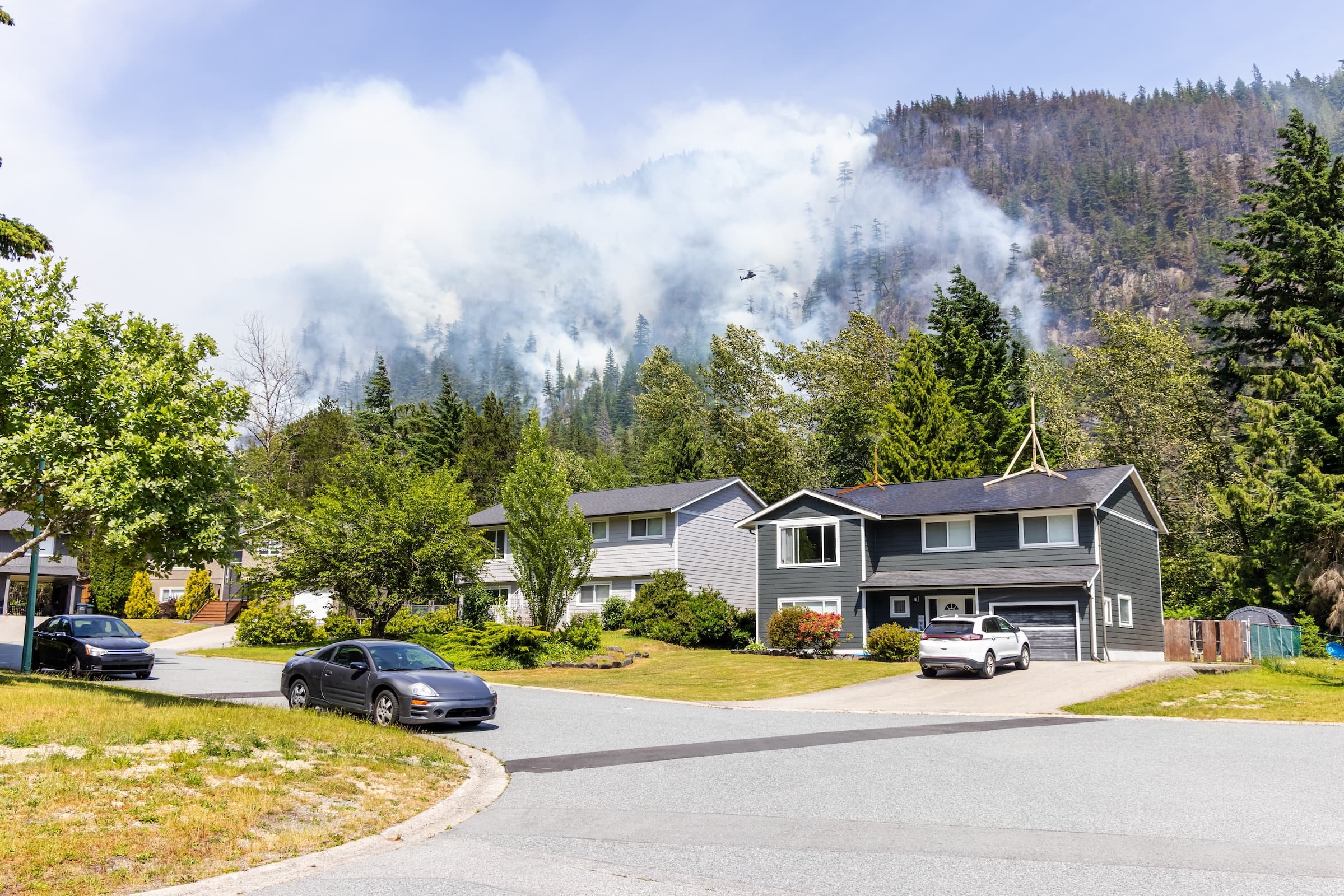 Suburban street with wildfire smoke in the background.